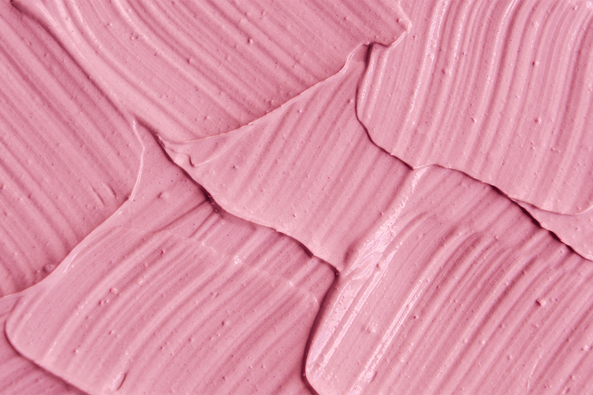 Pink cosmetic clay (facial mask, cream) texture close up, selective focus. Abstract background