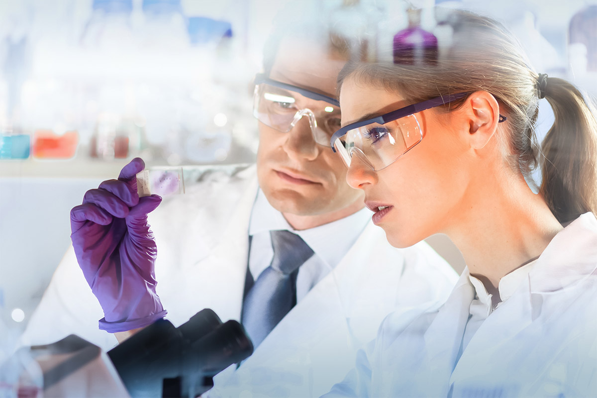 Attractive young scientist and her post doctoral supervisor looking at the microscope slide in the forensic laboratory.